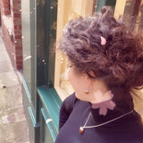 Person with curly hair and earrings standing near a glass door.