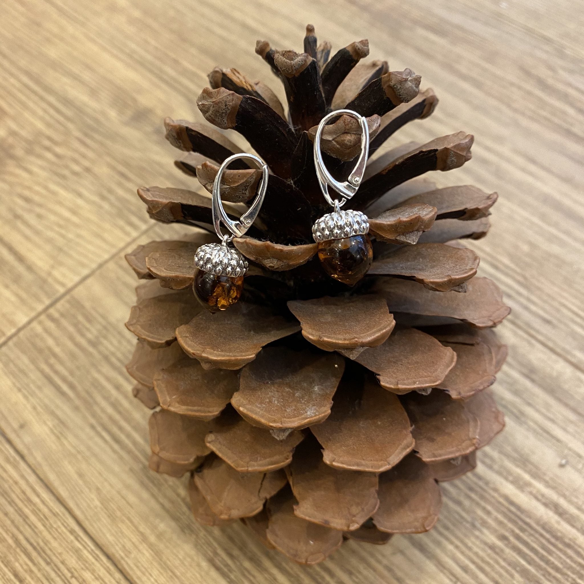 Silver earrings with amber beads on a pine cone