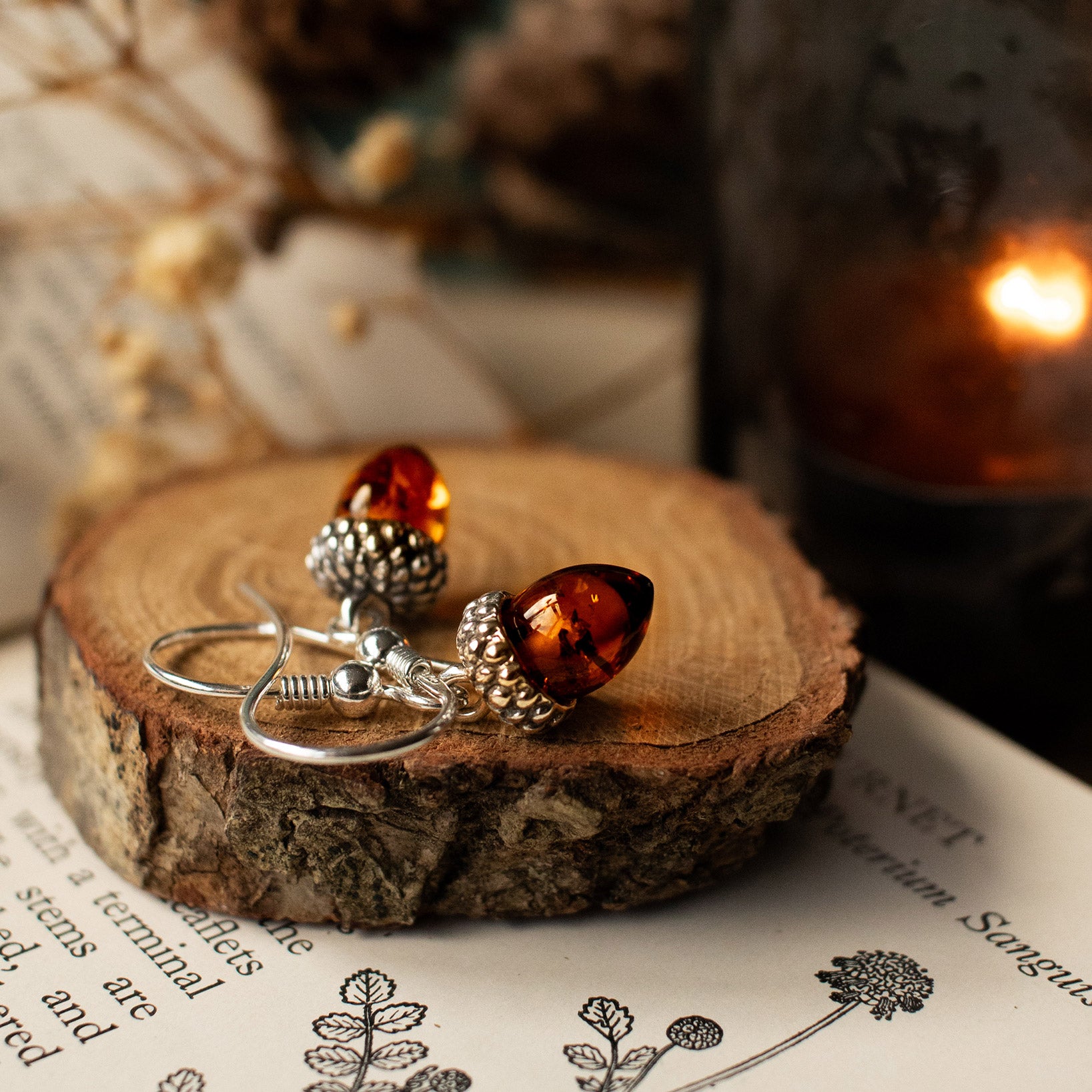Amber and silver earrings on a wooden surface with a blurred background