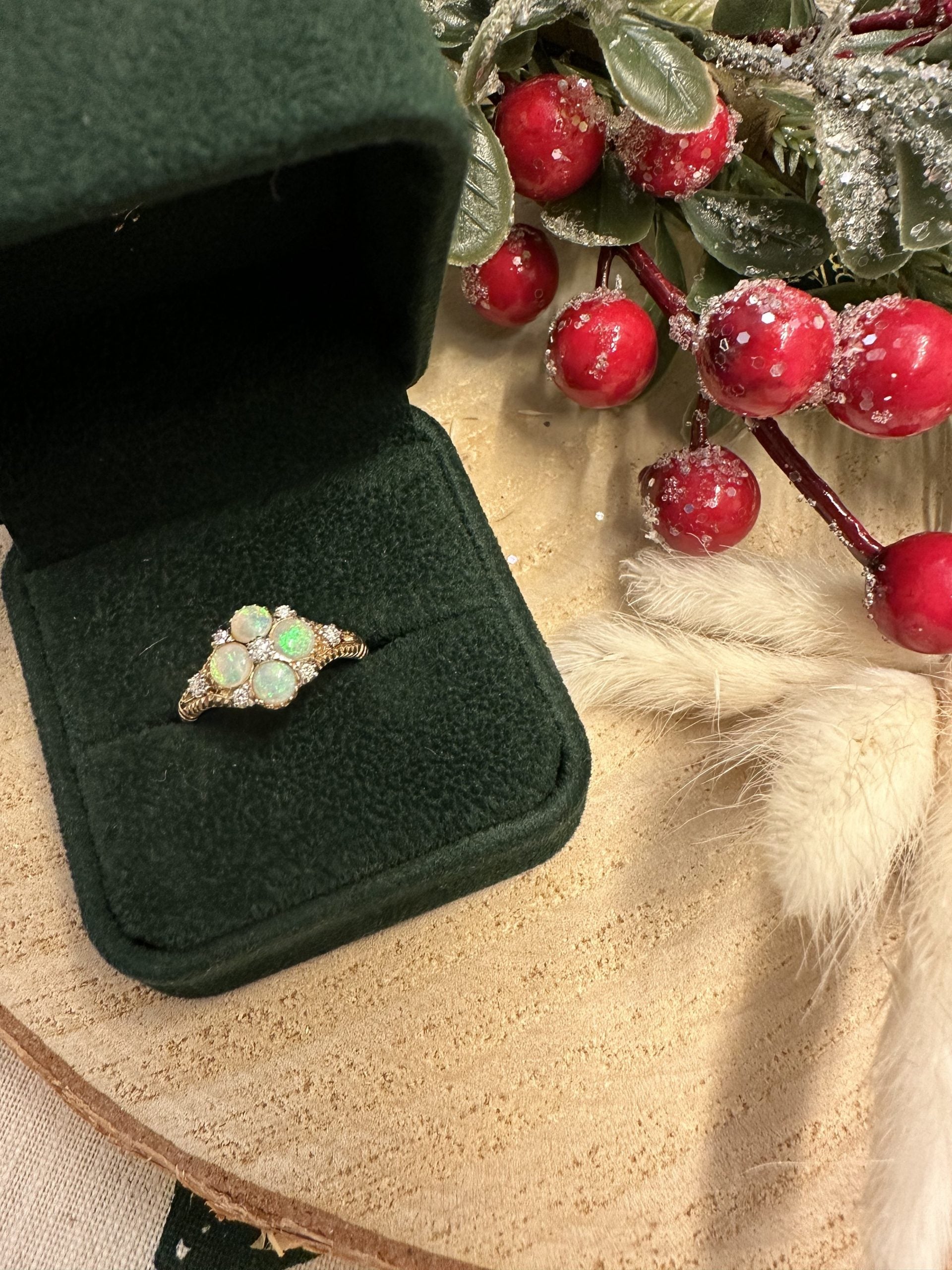 Opal ring in a green velvet box with red berries and greenery in the background