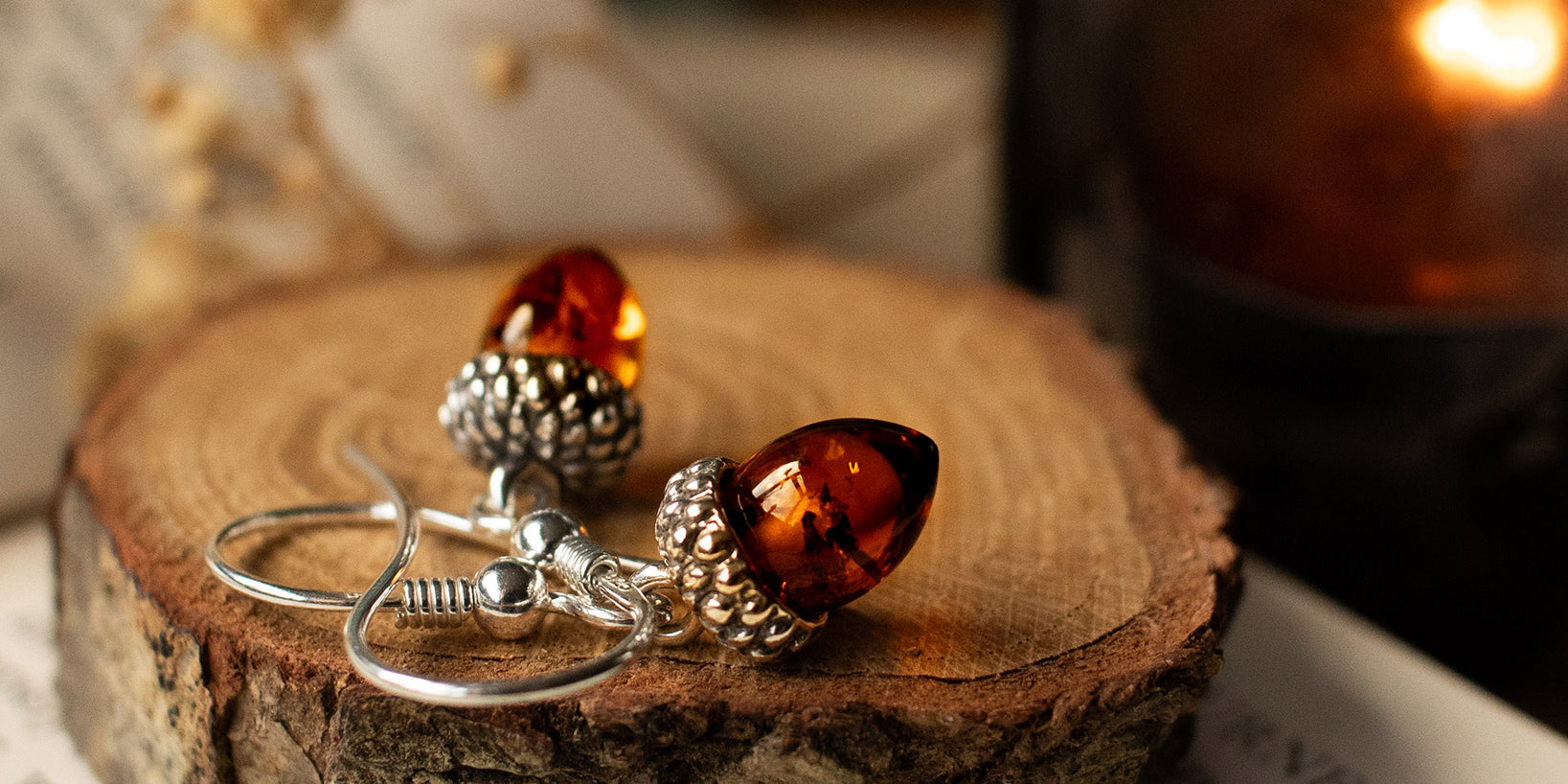 Amber and silver earrings on a wooden surface with a blurred background