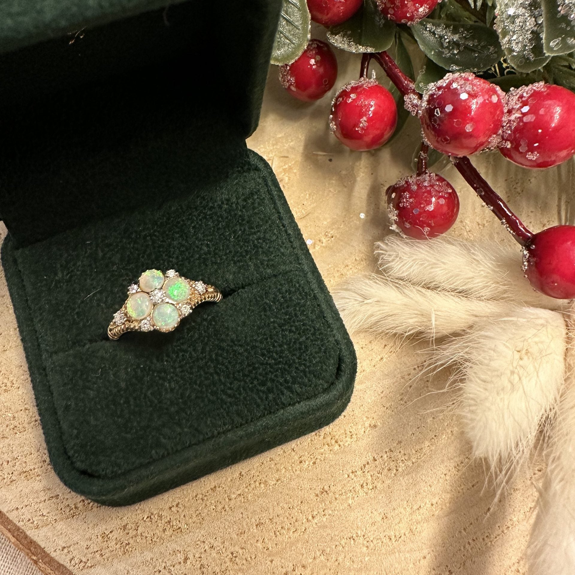 Opal ring in a green velvet box with red berries and greenery in the background