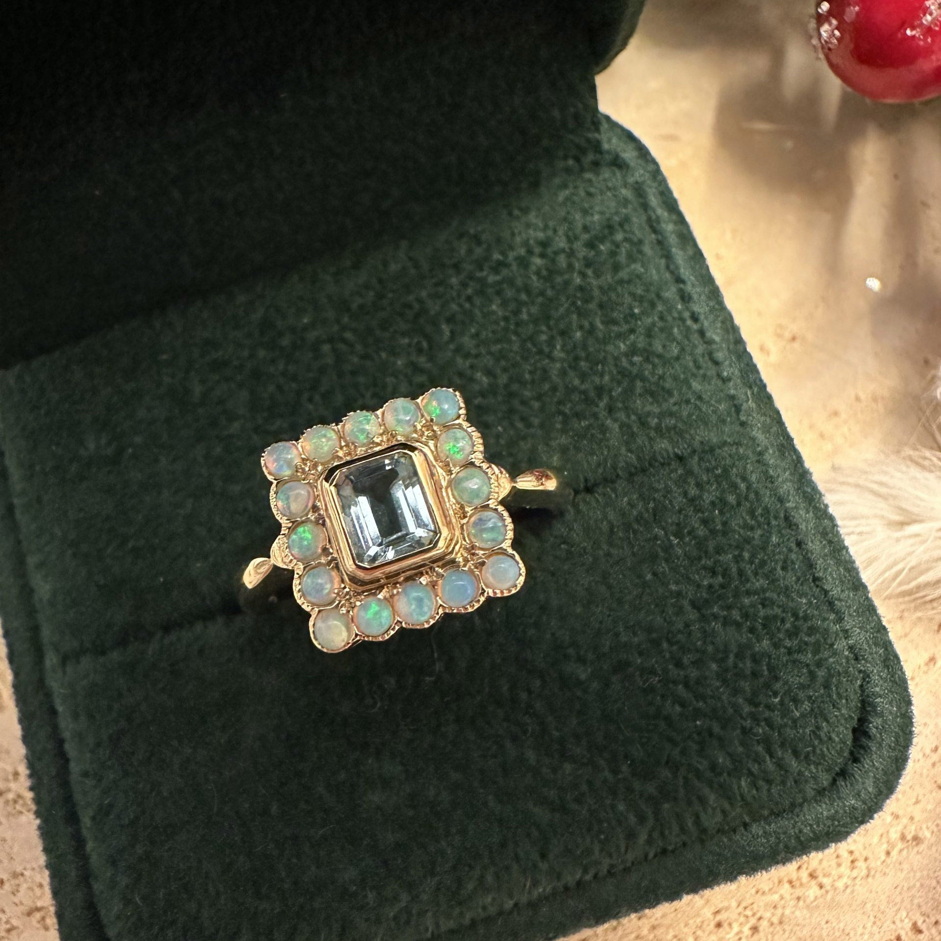 Gold ring with a central gemstone and smaller stones on a green cushion