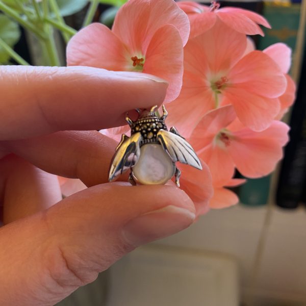mother of pearl bee brooch in front of flowers